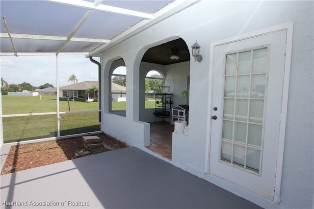 view of exterior entry with a yard and a patio