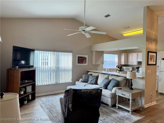 living area featuring vaulted ceiling, ceiling fan, visible vents, and light wood-style floors