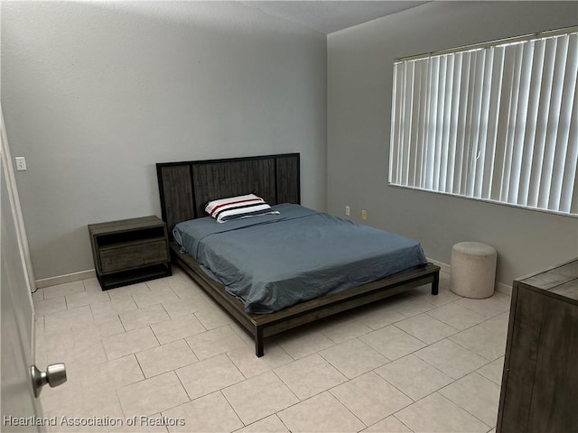 bedroom with light tile patterned floors and baseboards