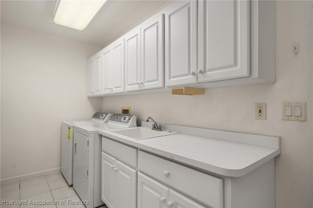 washroom with cabinet space, a sink, baseboards, light tile patterned floors, and washer and clothes dryer