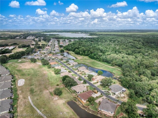 drone / aerial view featuring a water view, view of golf course, a residential view, and a wooded view