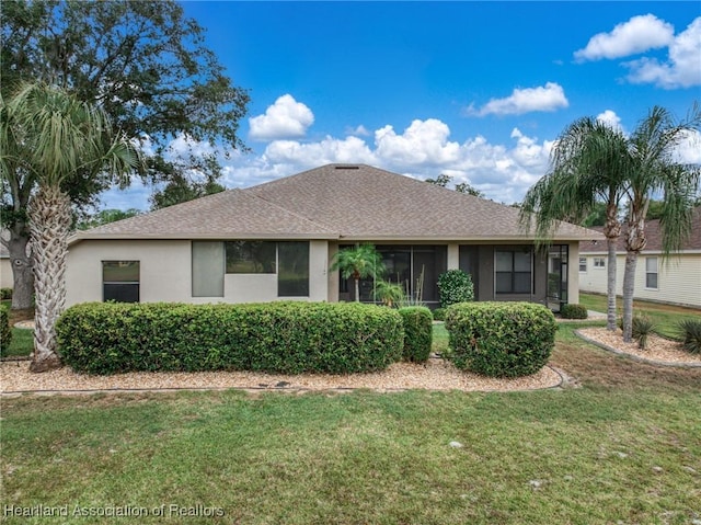 ranch-style home with a shingled roof, a front yard, and stucco siding