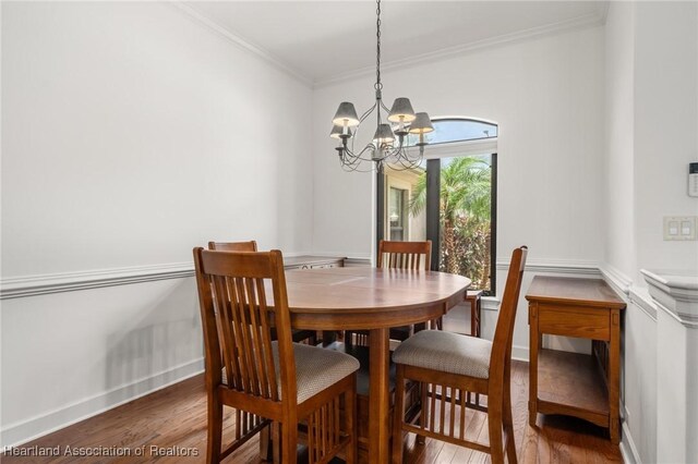 dining space featuring an inviting chandelier, ornamental molding, and wood finished floors