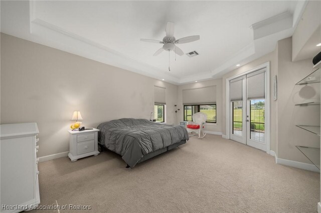 bedroom with light colored carpet, baseboards, visible vents, and a raised ceiling