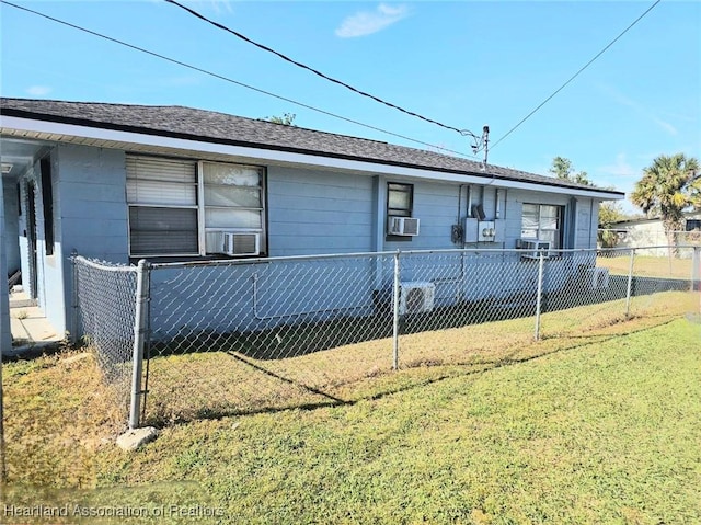 view of side of home featuring cooling unit, fence, a lawn, and a shingled roof