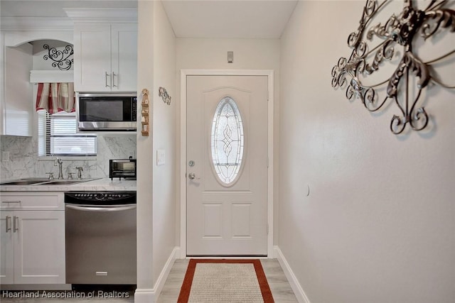 kitchen with backsplash, wood-type flooring, white cabinetry, and stainless steel appliances