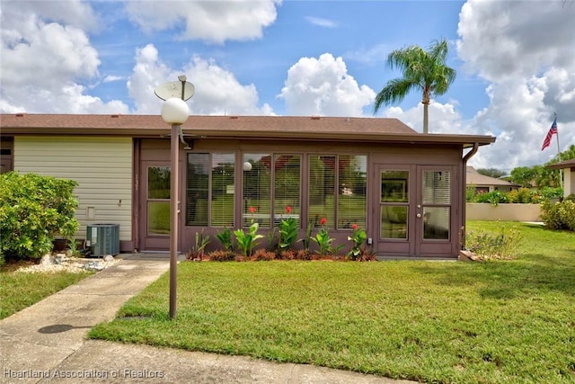 rear view of property featuring central AC unit and a yard