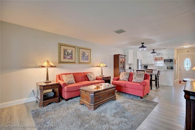 living room with light hardwood / wood-style floors and ceiling fan