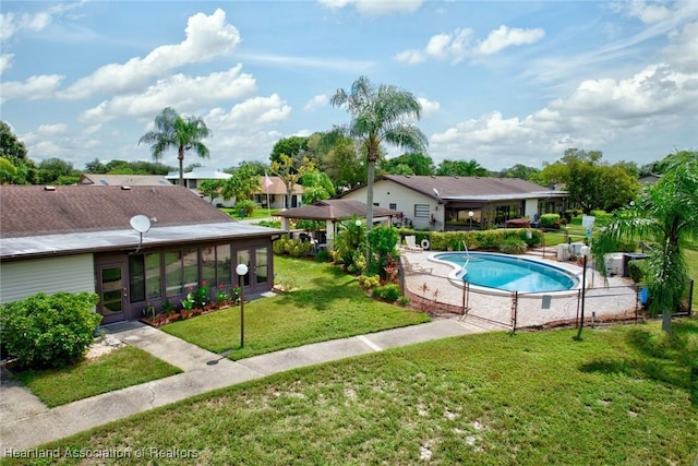 view of swimming pool with a lawn and a sunroom