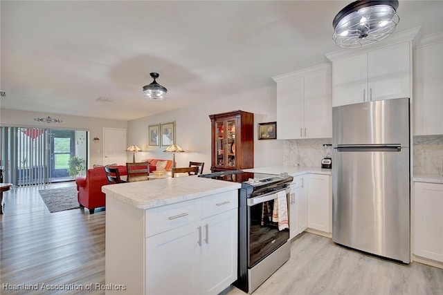 kitchen with light stone countertops, kitchen peninsula, stainless steel appliances, light hardwood / wood-style flooring, and white cabinetry