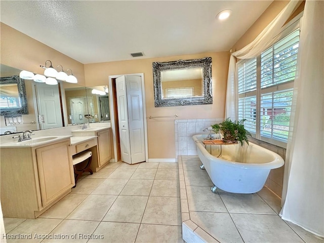 full bath with a freestanding tub, visible vents, a sink, and tile patterned flooring