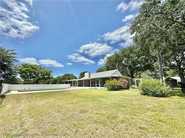 view of yard featuring fence, a fenced in pool, and a sunroom