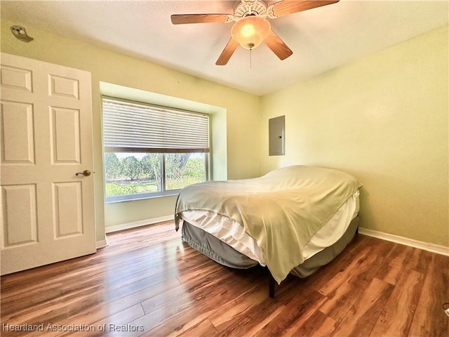 bedroom with baseboards, electric panel, a ceiling fan, and wood finished floors