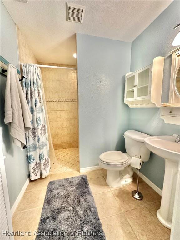 bathroom with visible vents, toilet, a textured ceiling, tile patterned floors, and a tile shower