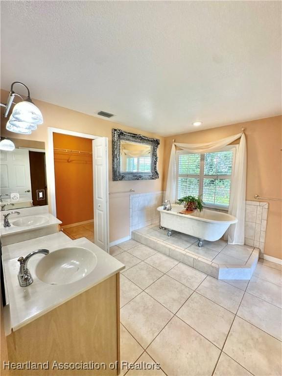 bathroom with a sink, a freestanding tub, double vanity, and visible vents