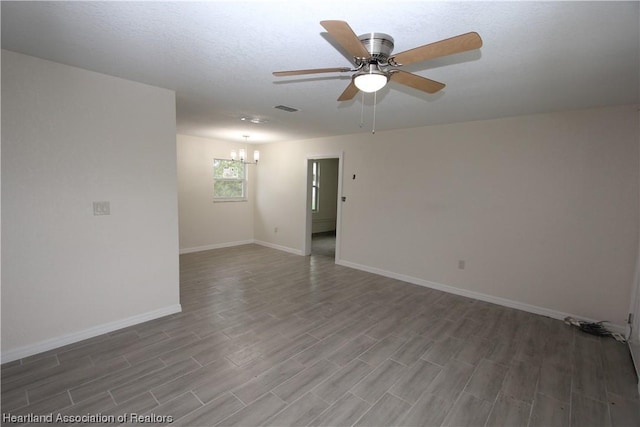 empty room featuring ceiling fan with notable chandelier and wood-type flooring