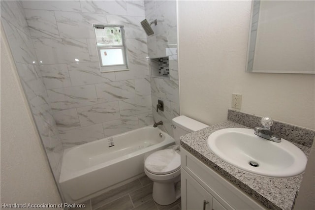 full bathroom featuring vanity, tiled shower / bath combo, and toilet