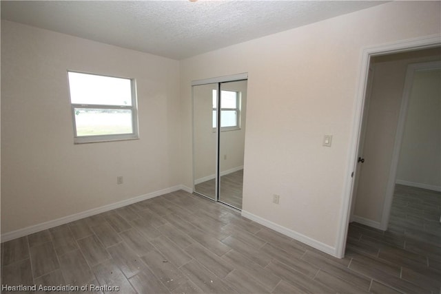 unfurnished bedroom with a closet, hardwood / wood-style floors, and a textured ceiling