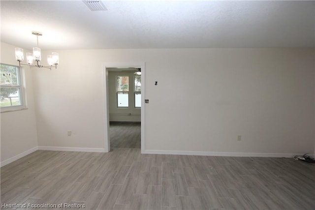 unfurnished room with ceiling fan with notable chandelier, wood-type flooring, and a wealth of natural light