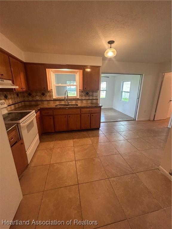 kitchen with white electric stove, sink, decorative backsplash, a textured ceiling, and light tile patterned flooring