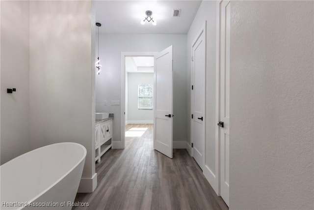 full bath featuring a soaking tub, visible vents, baseboards, wood finished floors, and vanity
