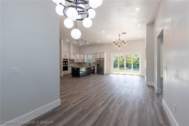 unfurnished living room featuring dark wood-style floors, recessed lighting, a chandelier, and baseboards