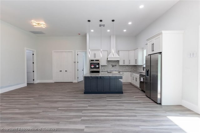 kitchen featuring a sink, stainless steel fridge, tasteful backsplash, premium range hood, and white cabinets