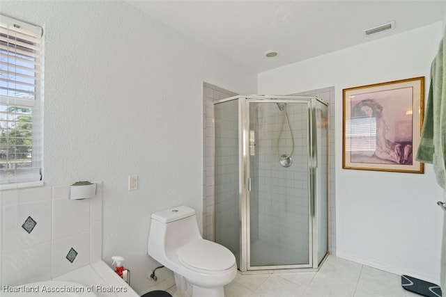 bathroom featuring tile patterned floors, toilet, and a shower with door