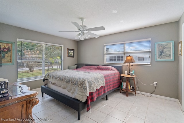 tiled bedroom with multiple windows, a textured ceiling, and ceiling fan