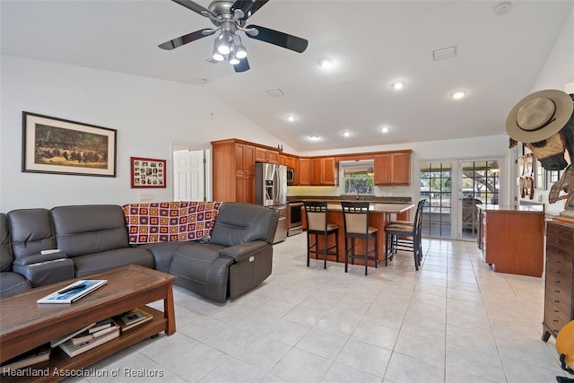 living room featuring lofted ceiling, ceiling fan, and light tile patterned flooring