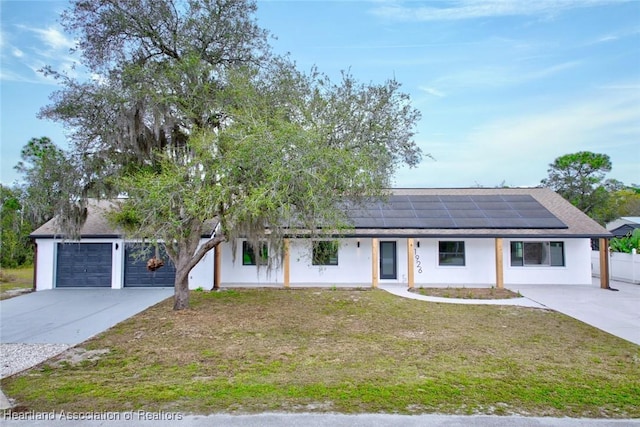 ranch-style home featuring stucco siding, roof mounted solar panels, a garage, driveway, and a front lawn