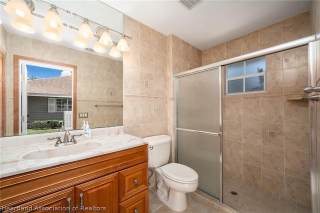 bathroom featuring a shower with shower door, a healthy amount of sunlight, tile walls, and toilet