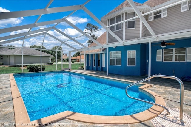 view of swimming pool featuring glass enclosure, ceiling fan, and a patio area