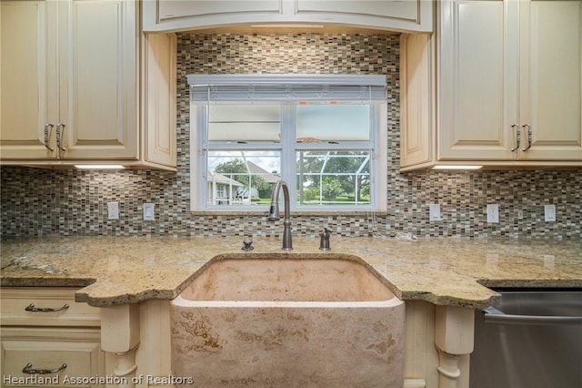 kitchen featuring backsplash, light stone countertops, sink, and cream cabinetry