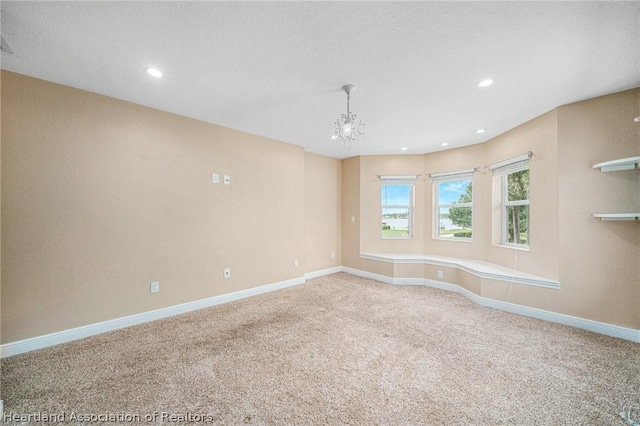 carpeted spare room featuring an inviting chandelier