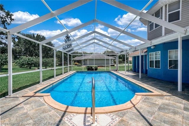 view of swimming pool with a lanai, a patio area, and a lawn