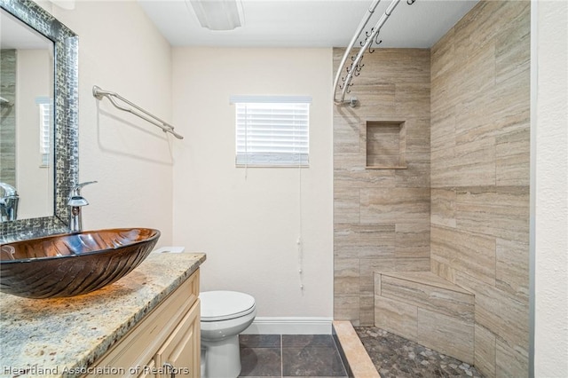 bathroom featuring tile patterned flooring, vanity, tiled shower, and toilet