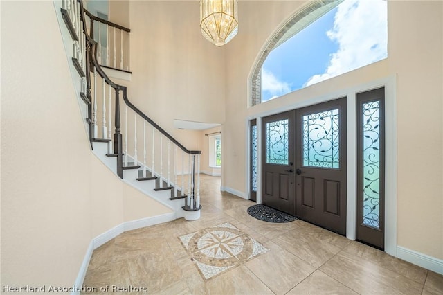 entrance foyer featuring french doors, a high ceiling, and an inviting chandelier