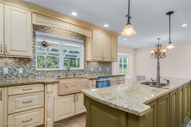 kitchen featuring dishwasher, sink, light stone countertops, and decorative light fixtures