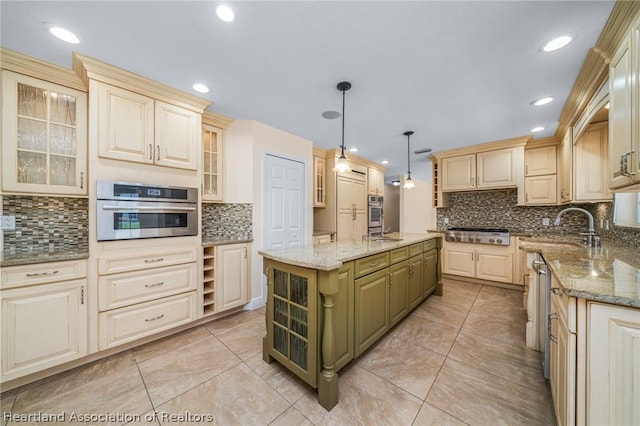 kitchen with light stone counters, stainless steel gas cooktop, sink, pendant lighting, and a center island