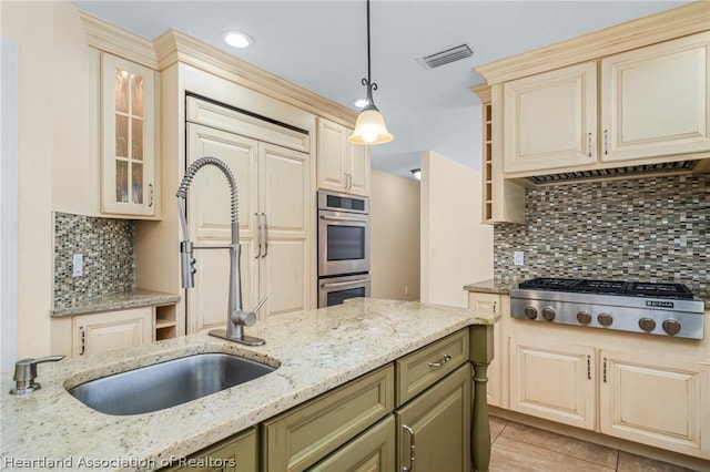 kitchen featuring sink, hanging light fixtures, light stone counters, decorative backsplash, and appliances with stainless steel finishes