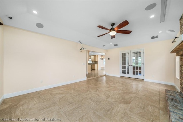 unfurnished living room featuring a brick fireplace, ceiling fan, and french doors