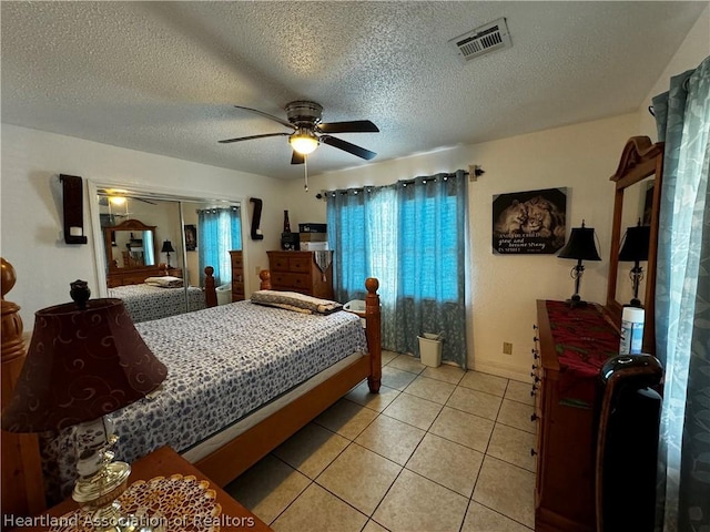 bedroom featuring light tile patterned floors, a textured ceiling, a closet, and ceiling fan