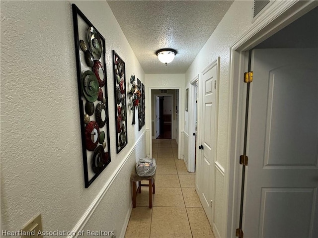 hallway featuring light tile patterned floors and a textured ceiling