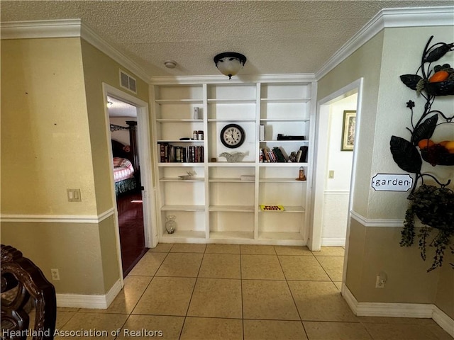 corridor featuring light tile patterned floors, a textured ceiling, built in features, and crown molding