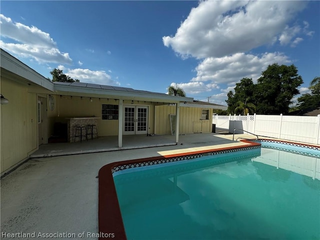 view of pool featuring french doors, a bar, and a patio