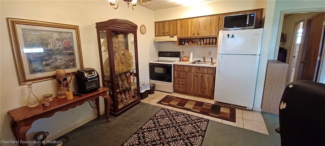 kitchen with under cabinet range hood, range with electric cooktop, a sink, freestanding refrigerator, and stainless steel microwave