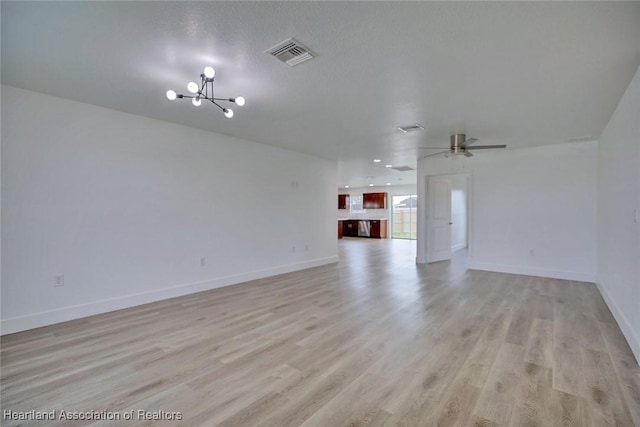 unfurnished living room with a textured ceiling, light hardwood / wood-style floors, and ceiling fan with notable chandelier