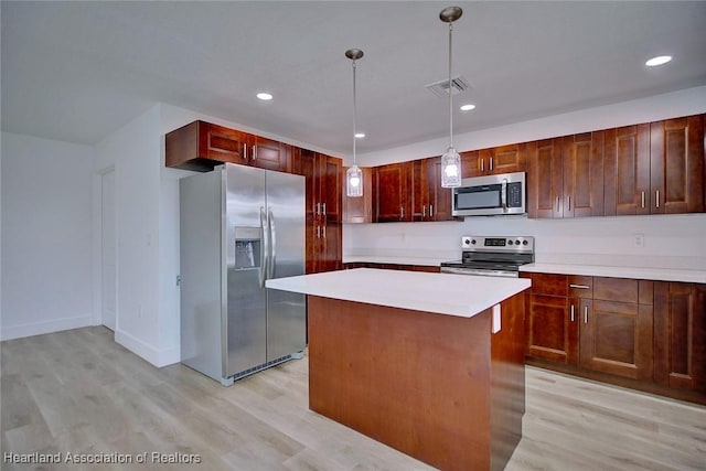 kitchen featuring a center island, light wood-type flooring, hanging light fixtures, and appliances with stainless steel finishes