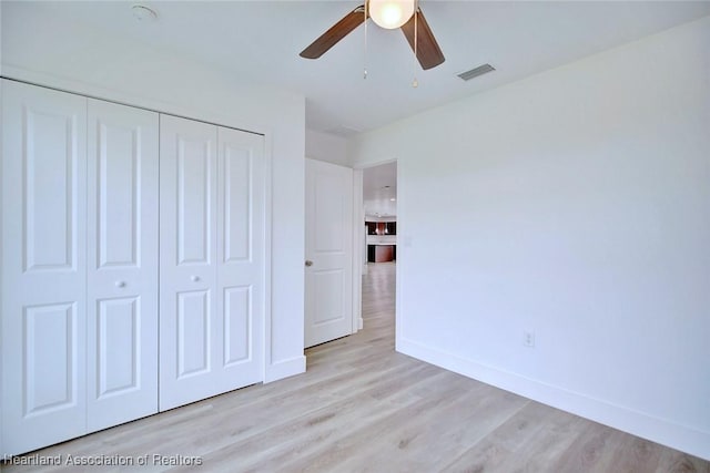 unfurnished bedroom with ceiling fan, a closet, and light hardwood / wood-style flooring